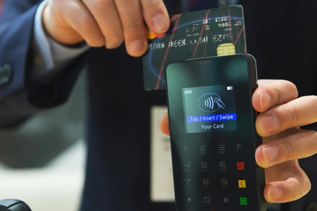Guest tapping a card on a payment terminal, credit card processing for hotels