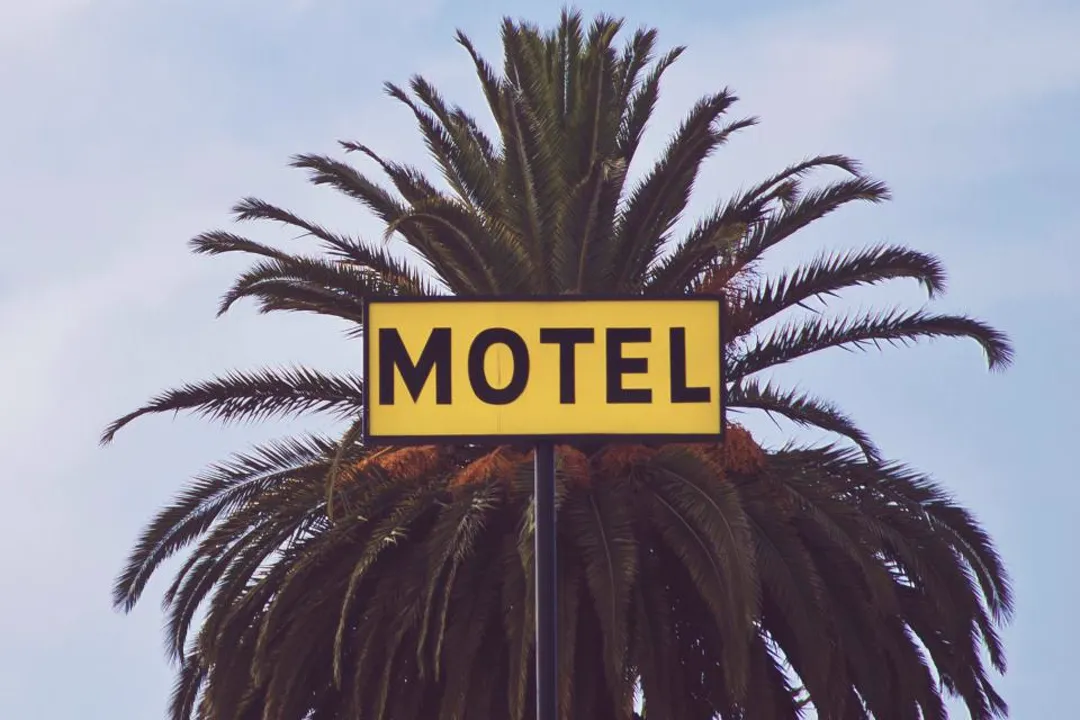 Motel sign in front of a palm tree, credit card processing for motels and inns